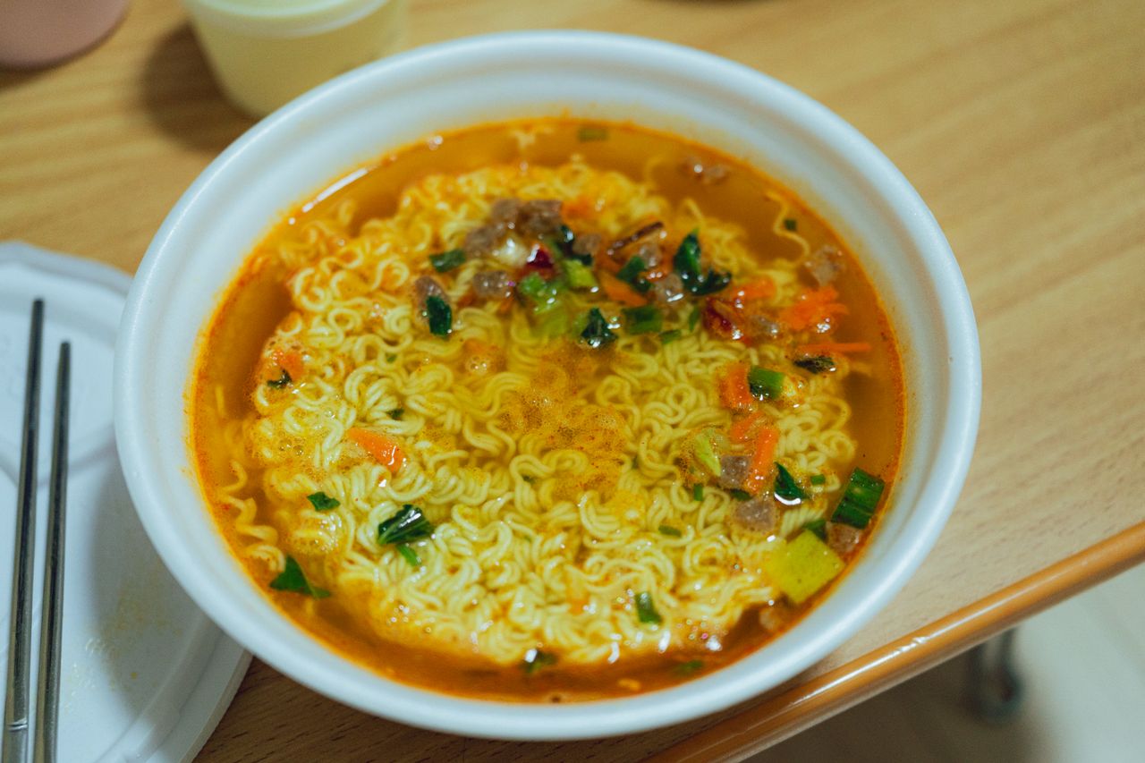 Crafting Captivating Headlines: Your awesome post title goes here Close-up of a bowl of spicy Korean ramen with vegetables on a wooden table.